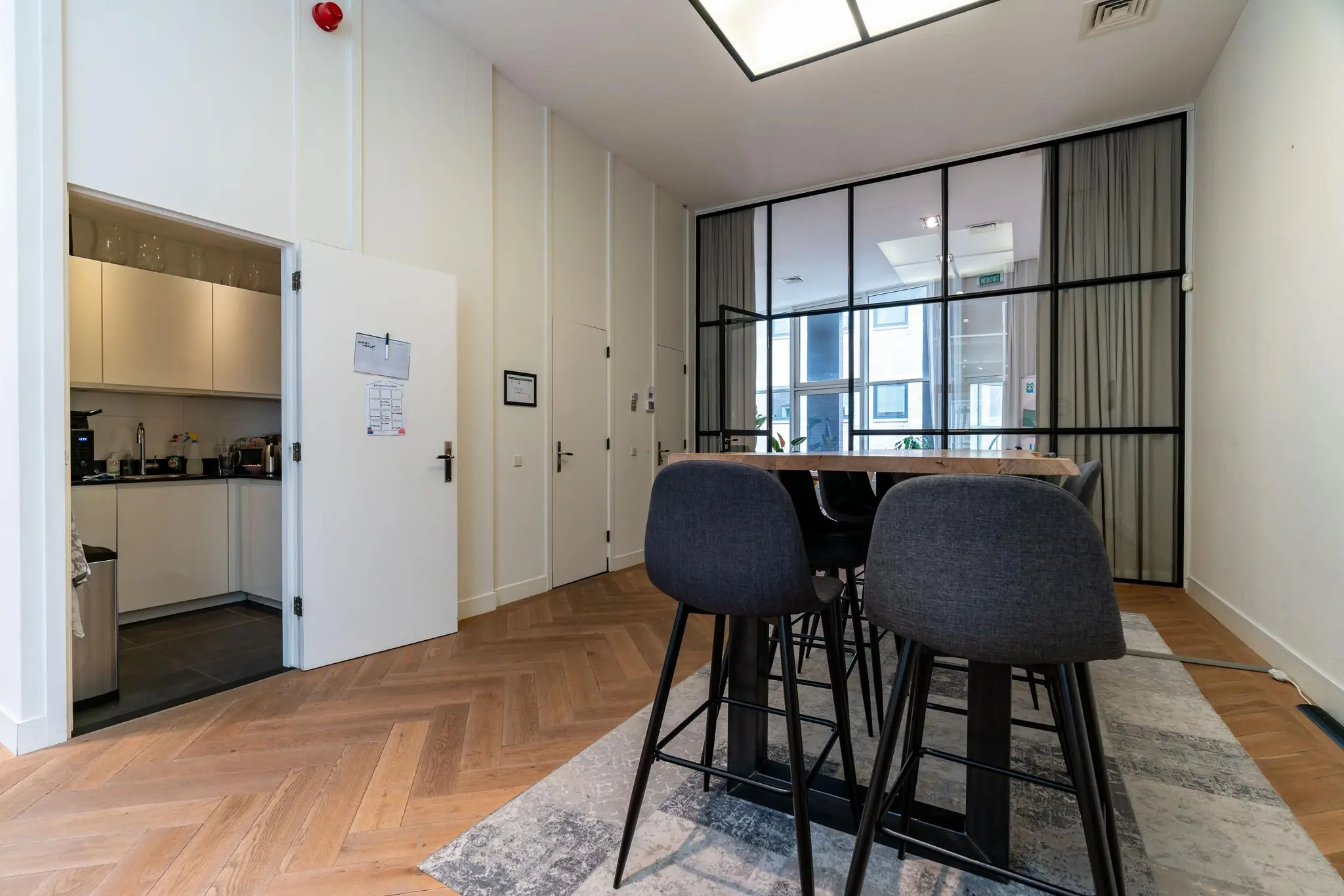 Moderne vergaderruimte aan de Lange Vijverberg met hoge krukken, glazen wand en open keuken.